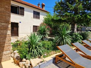 Eine Terrasse mit zwei Holzstühlen und Pflanzen vor einem Gebäude in der Unterkunft Vila Ivana Jadranovo in Jadranovo