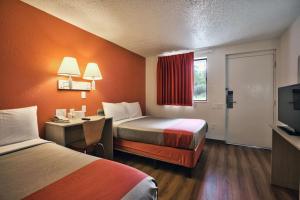 a hotel room with two beds and a desk and a television at Loyalty Inn Tallahassee in Tallahassee