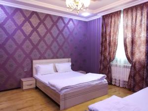 a bedroom with a bed and a purple wall at Elnur small villa in Daşca