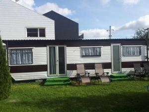 a house with chairs sitting in the front yard at Domek Holenderski in Mielno