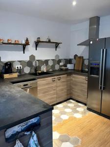 uma cozinha com um frigorífico de aço inoxidável e armários de madeira em Un doux refuge em LʼHospitalet-près-lʼAndorre