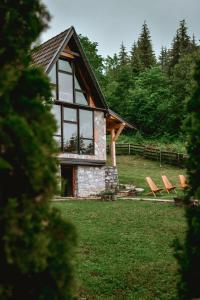 a building with windows and chairs in a field at Planinska Koliba ABA-TARA in Bajina Bašta