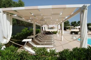 a group of lounge chairs under a pavilion next to a pool at Tenuta Verdolivo in Ostuni