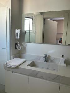 Baño blanco con lavabo y espejo en Costa Sul Beach Hotel en Balneario Camboriú