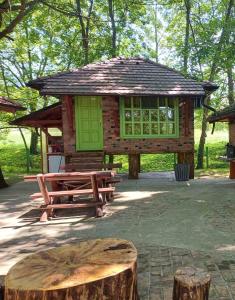 a small wooden cabin with a table and a tree stump at Kutak na Drini in Mali Zvornik