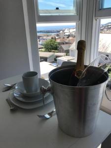 un cubo con una botella de champán sentado en una mesa junto a una ventana en Modern Studio Apartment with harbour views, en Penzance