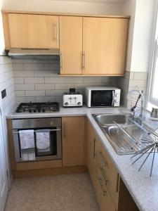 cocina con fregadero y fogones horno superior en Modern Studio Apartment with harbour views, en Penzance