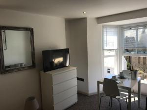 una sala de estar con TV en un tocador y una mesa en Modern Studio Apartment with harbour views, en Penzance