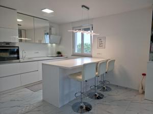a white kitchen with a counter and two stools at Luxury Apartment Umag in Umag