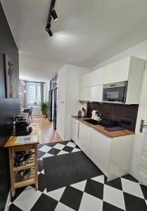 a kitchen with white cabinets and a black and white checkered floor at Holiday Apartment Old Town Gdansk with a Jacuzzi in Gdańsk