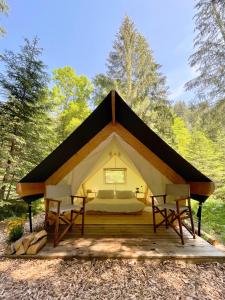 a tent in the woods with a bed and two chairs at Glamping Tent Water Village Rogla in Oplotnica