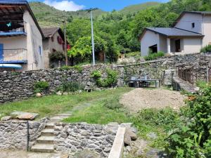 un jardín con una pared de piedra y una mesa en Grand gîte au coeur d'un charmant village, en Miglos