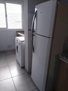 a white refrigerator in a kitchen with a washing machine at Antonia in Guaymallen