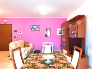 una sala de estar con una pared de color rosa y una mesa. en La casa di Marcella en Pescara