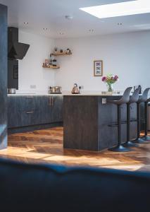 a kitchen with a counter with stools at Three Oaks in Winkleigh