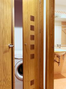 a bathroom with a washing machine and a wooden door at JoaquinLoriga18 By Vigovacaciones in Vigo
