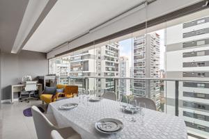 une salle à manger avec une table et une grande fenêtre dans l'établissement Magníficos Ap Luxo - 43mts e 63mts, 1 ou 2 Qtos, à São Paulo