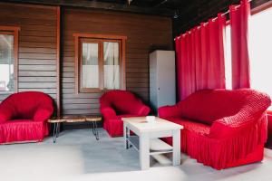 2 rote Stühle und ein Tisch auf einer Veranda in der Unterkunft Pensiunea Suzanne Băile Figa in Beclean