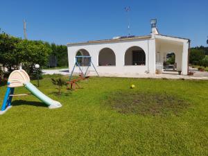 - une aire de jeux avec toboggan dans une cour avec un bâtiment dans l'établissement Li tufi Salento casa vacanze Puglia, à Monteroni di Lecce