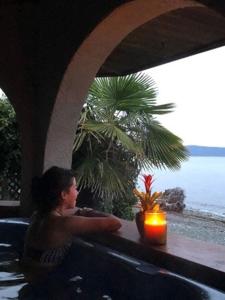 a woman sitting in a bath tub with a candle at Qualicum Breeze Beach Resort in Qualicum Beach