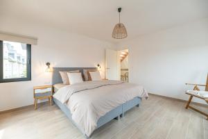 a white bedroom with a large bed and a table at Villa Dianga (De Haan) in De Haan