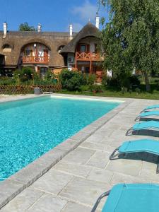 a swimming pool with lounge chairs in front of a house at Emese Apartman Cserszegtomaj in Cserszegtomaj