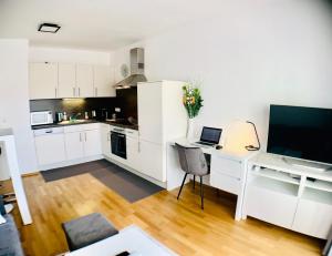 eine Küche mit weißen Schränken und einem Schreibtisch mit einem Laptop in der Unterkunft Apartment Centro - YOUR 2nd HOME in GRAZ in Graz