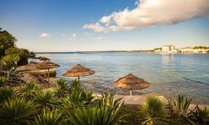 um grupo de guarda-sóis numa praia junto à água em Boutique Hotel Mauro em Porec