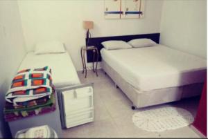 a bedroom with two beds and a table with a lamp at Pousada Villas in Sorocaba