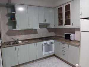 a kitchen with white cabinets and a sink and a microwave at Apartamento RUAL in Sanxenxo
