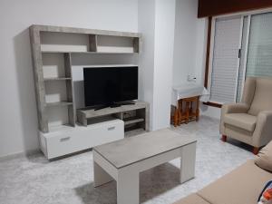 a living room with a tv and a couch and a table at Apartamento RUAL in Sanxenxo