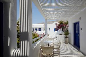 a white porch with white chairs and a table on it at Kouros Village Hotel - Adults Only in Perissa
