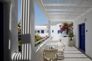 a white porch with white chairs and a table on it at Kouros Village Hotel - Adults Only in Perissa