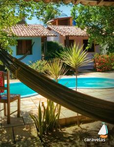 een hangmat voor een huis en een zwembad bij Pousada Caravelas in São Miguel do Gostoso