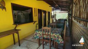 een tafel en stoelen in een kamer met een gele muur bij Pousada Caravelas in São Miguel do Gostoso