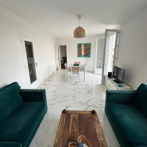 a living room with two green couches and a table at La Maison d'Heidi in Saint-Georges-sur-la-Prée