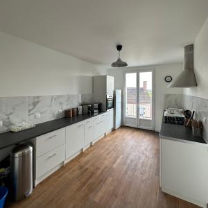 a kitchen with white cabinets and a wooden floor at La Maison d'Heidi in Saint-Georges-sur-la-Prée