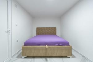 Bett mit violetter Bettwäsche in einem weißen Zimmer in der Unterkunft Stojkovic Family Apartments in Tivat