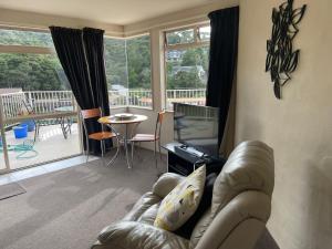 a living room with a leather couch and a television at Absolute Bliss Apartments in Paihia