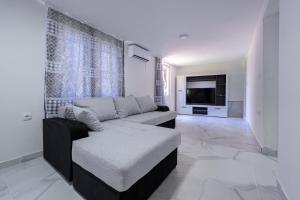 ein Wohnzimmer mit einem Sofa und einem Flachbild-TV in der Unterkunft Stojkovic Family Apartments in Tivat