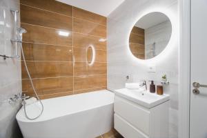 a bathroom with a white tub and a sink and a mirror at Charming Family Haven in Oradea +25 photos
