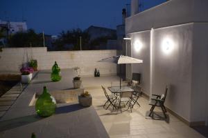 a patio with a table and chairs and an umbrella at Il Giardino dei Ricordi in Alberobello