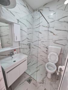 a white bathroom with a toilet and a sink at Kahari Apartments in Ulcinj