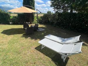 a white chair and an umbrella on the grass at Le Calende di Maggio di Assisi in Palazzo