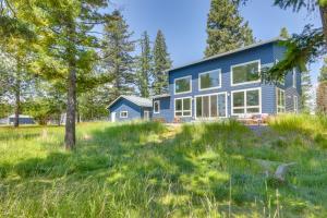 a blue house in a field with trees at Columbia Falls Home with Patio Near Glacier NP! in Columbia Falls