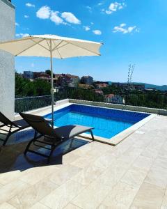 a chair and an umbrella next to a swimming pool at Apartman Iva in Tivat