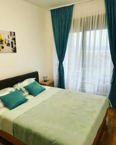 a bedroom with a bed with blue pillows and a window at Apartman Iva in Tivat +5 photos