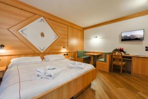 Un dormitorio con una cama con toallas blancas. en Chalet Pineta relax location, en Canazei
