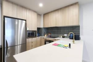 a kitchen with a sink and a refrigerator at OHANA - SeaHome in Batemans Bay
