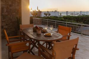 una mesa de madera con copas de vino y un bol de fruta en Aelia seafront house, en Kokkíni Khánion